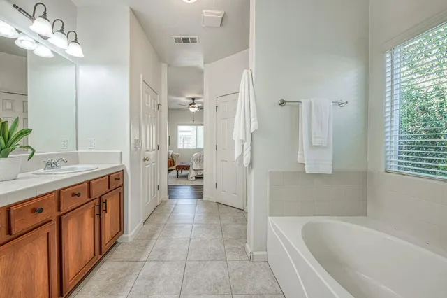 a bathroom with a tub sink shower and two mirror