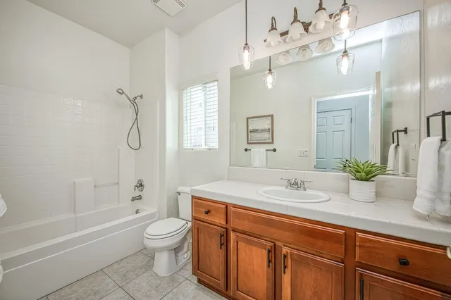 a bathroom with a granite countertop sink a toilet a mirror a bathtub and shower