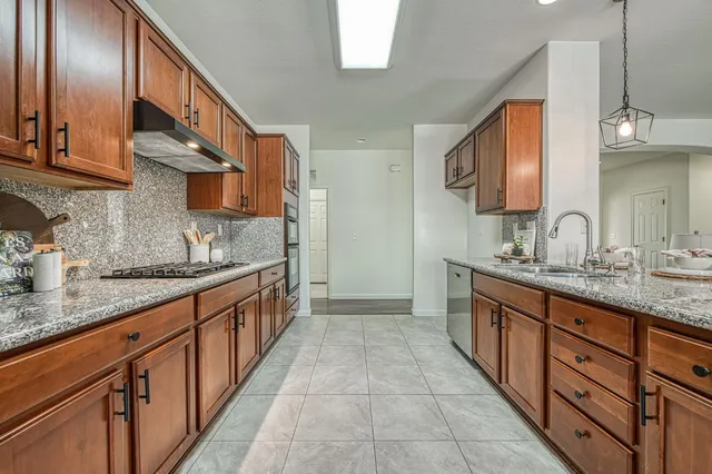 a large kitchen with stainless steel appliances granite countertop a sink and cabinets