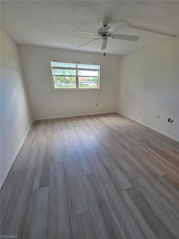 160 Turtle Lake Court, Unit 209 Naples, FL 34105 - Photo 13 of 26 an empty room with wooden floor and windows