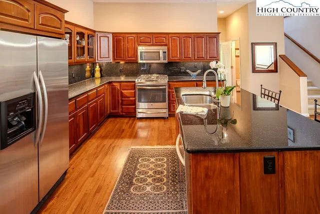 a kitchen with stainless steel appliances granite countertop a sink a stove and wooden floor