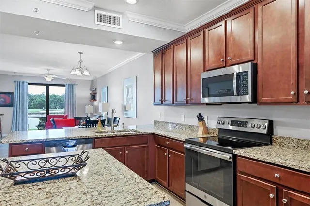 a kitchen with stainless steel appliances granite countertop a sink stove refrigerator and microwave