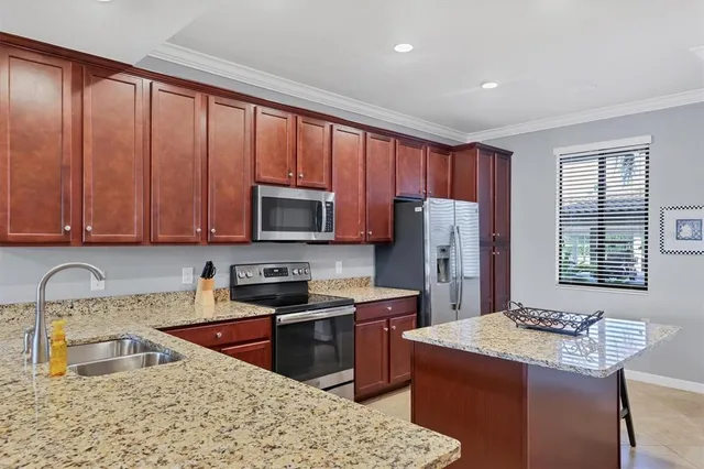 a kitchen with kitchen island granite countertop a sink counter top space appliances and cabinets