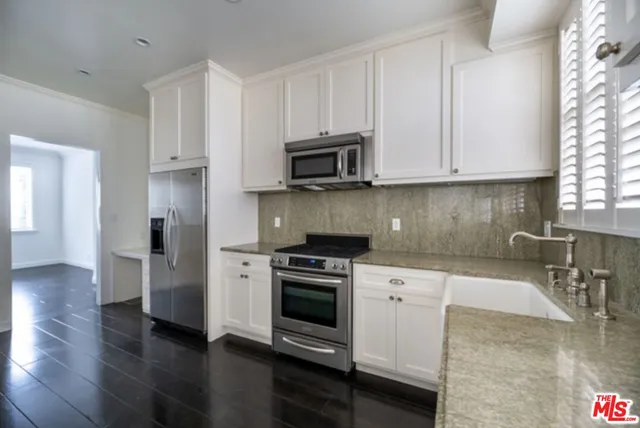 a kitchen with granite countertop a stove a sink and a microwave