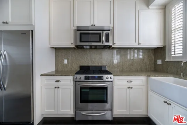 a kitchen with granite countertop white cabinets and stainless steel appliances