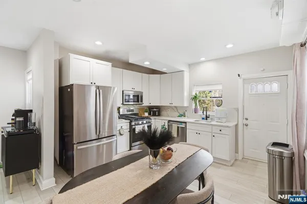 a kitchen with refrigerator a sink dishwasher a dining table and chairs with wooden floor
