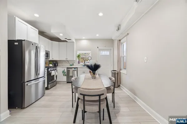 a kitchen with stainless steel appliances a refrigerator a stove a dining table and chairs
