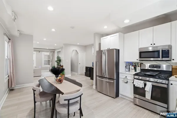 a kitchen with stainless steel appliances kitchen island granite countertop a refrigerator oven a stove a sink a dining table and chairs with wooden floor