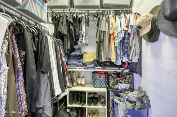 a view of walk in closet with clothes and shoes