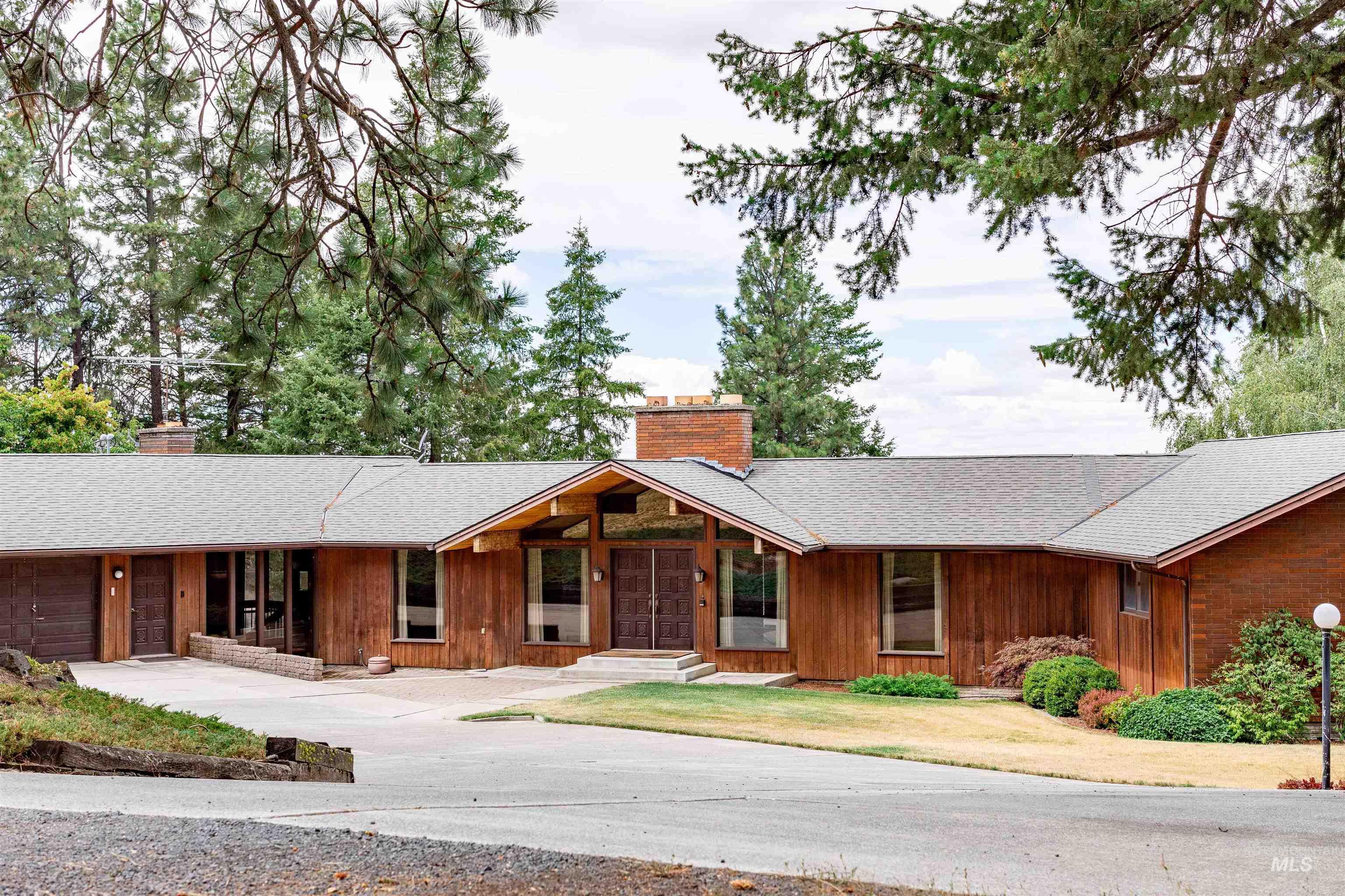 View of front of home featuring a chimney, a shingled roof, an attached garage, and concrete driveway
