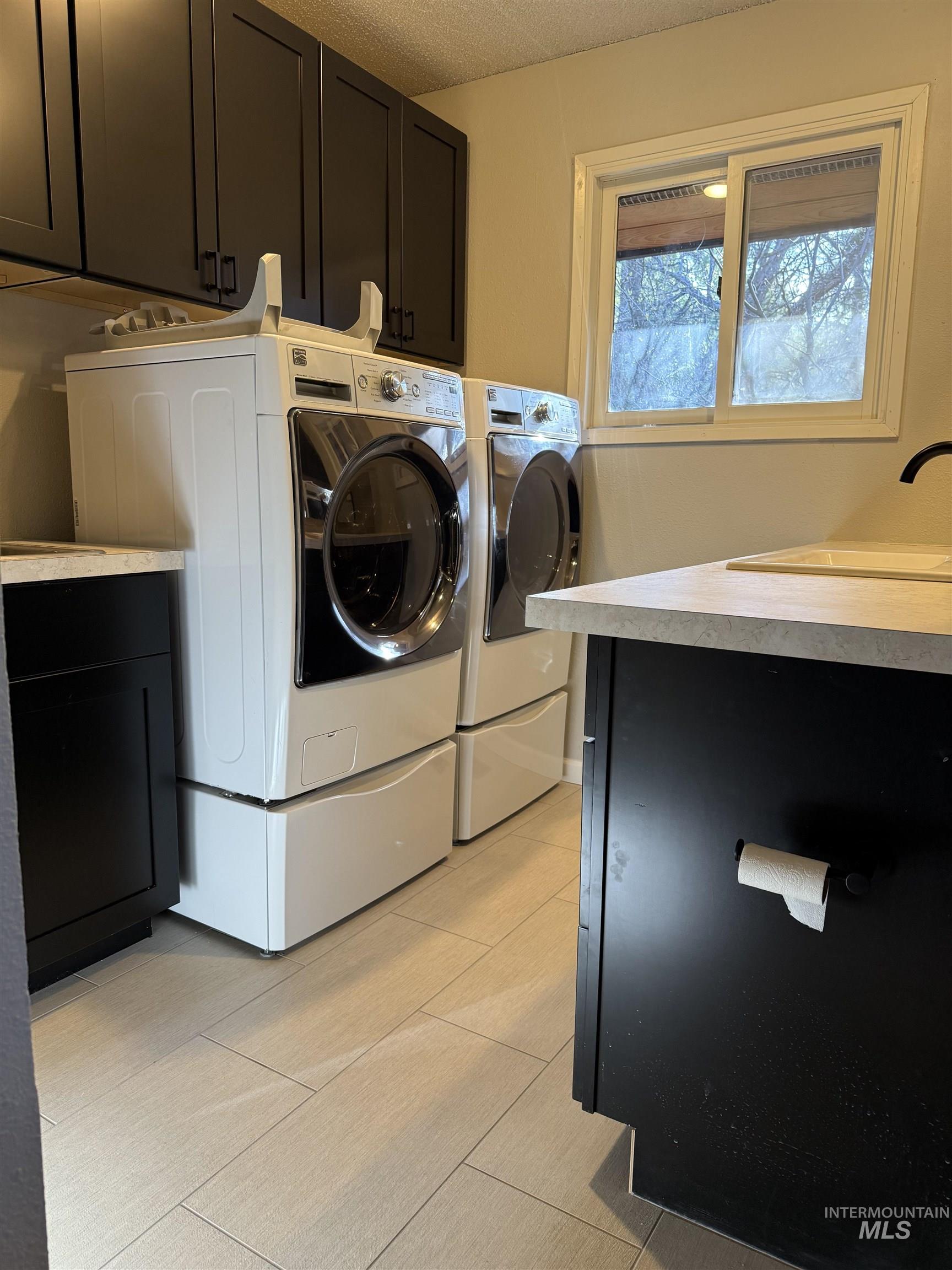1050 Paradise Ridge Road Moscow, ID 83843 - Photo 12 of 49 Laundry room featuring washer and dryer, cabinet space, and a textured ceiling