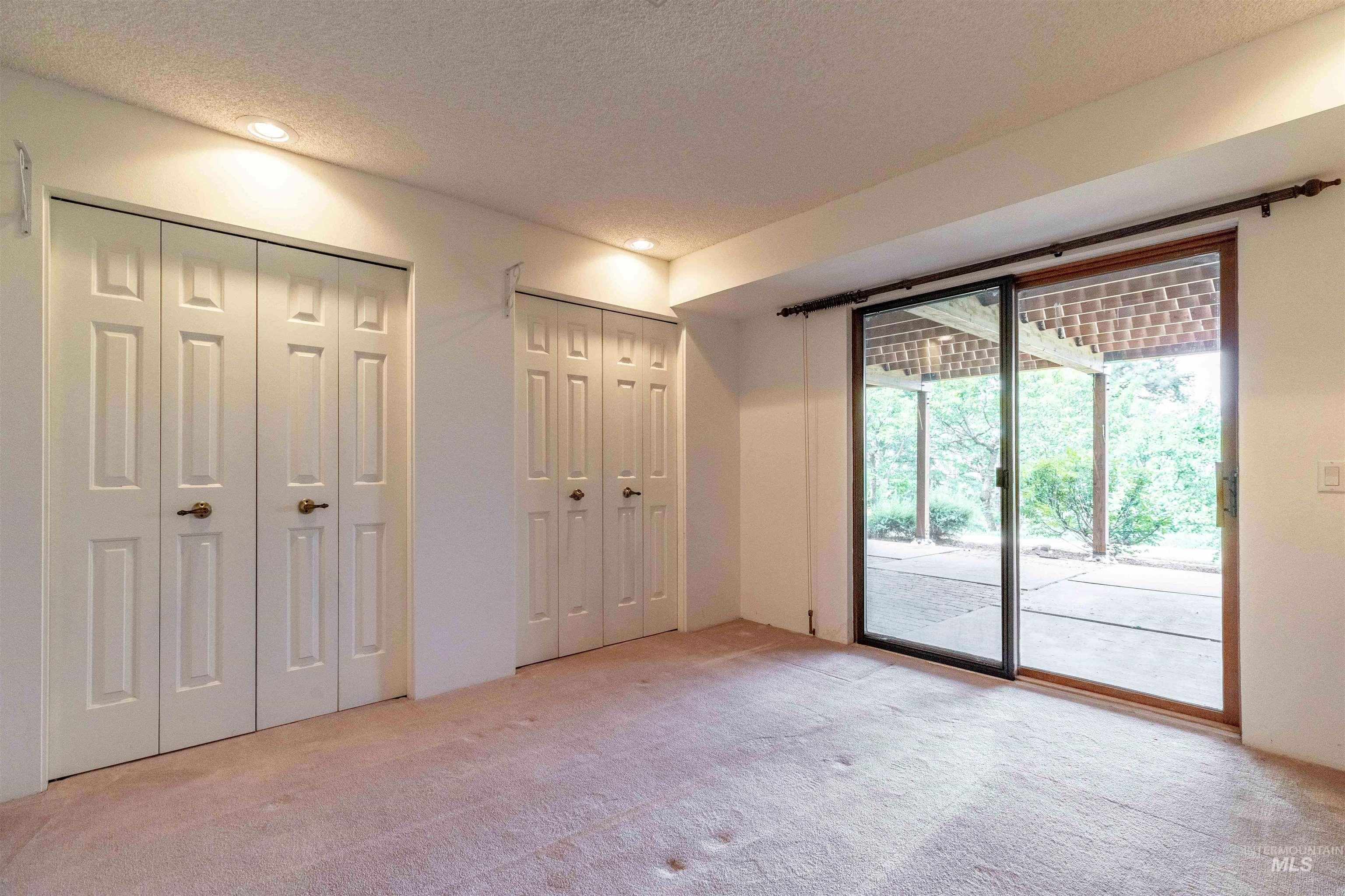 1050 Paradise Ridge Road Moscow, ID 83843 - Photo 16 of 49 Unfurnished bedroom featuring multiple closets, access to exterior, light colored carpet, a textured ceiling, and recessed lighting