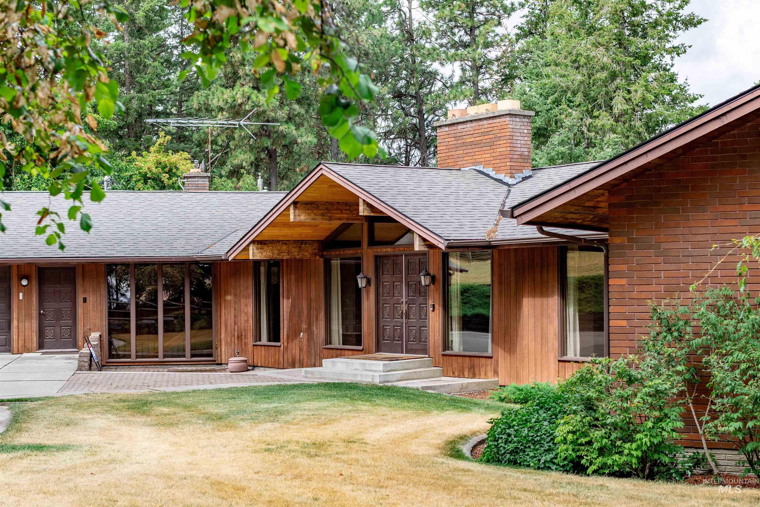 1050 Paradise Ridge Road Moscow, ID 83843 - Photo 2 of 49 View of front of house with a chimney, roof with shingles, a front lawn, and covered porch