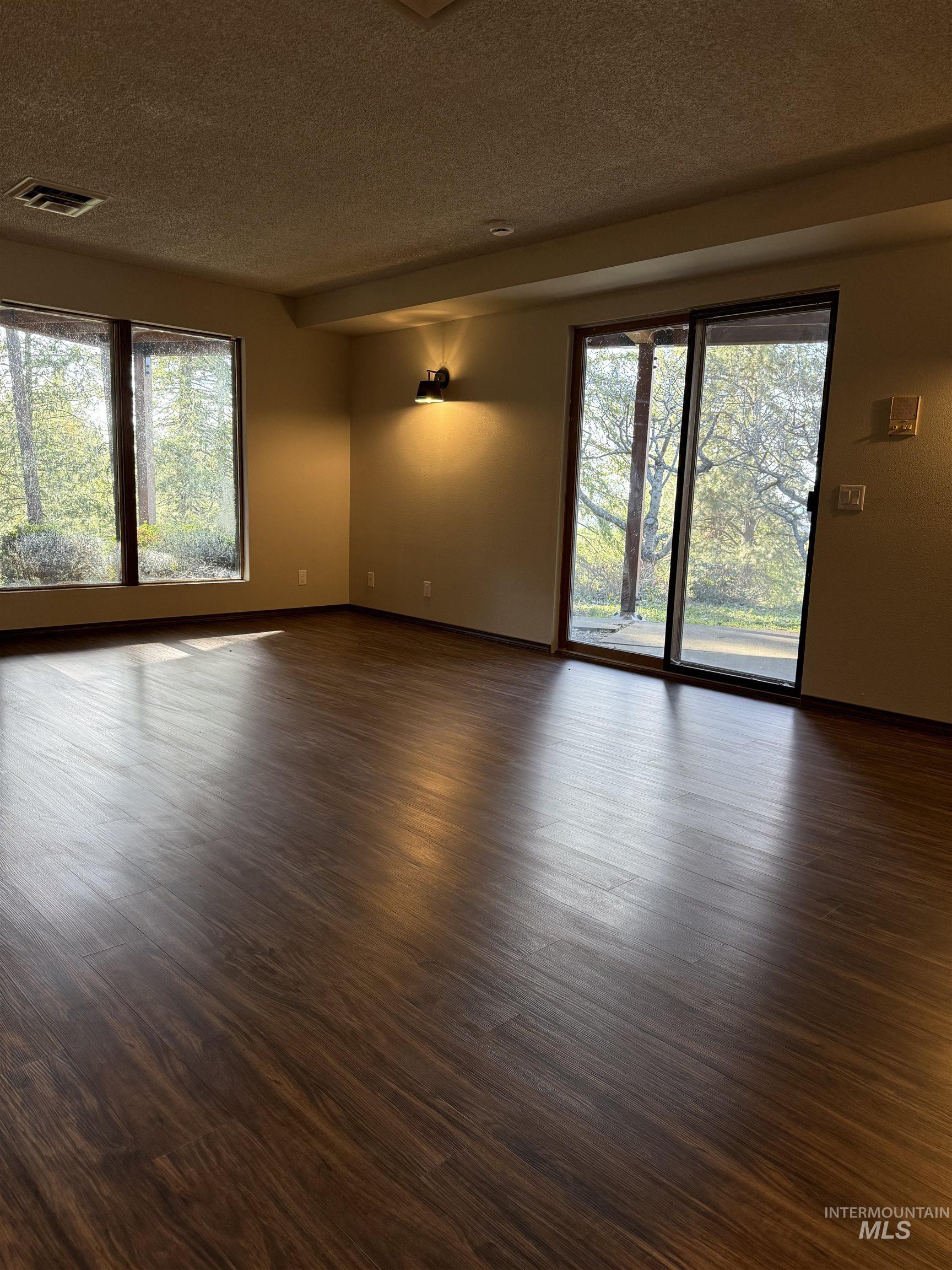 1050 Paradise Ridge Road Moscow, ID 83843 - Photo 25 of 49 Empty room with dark wood finished floors, a textured ceiling, and plenty of natural light