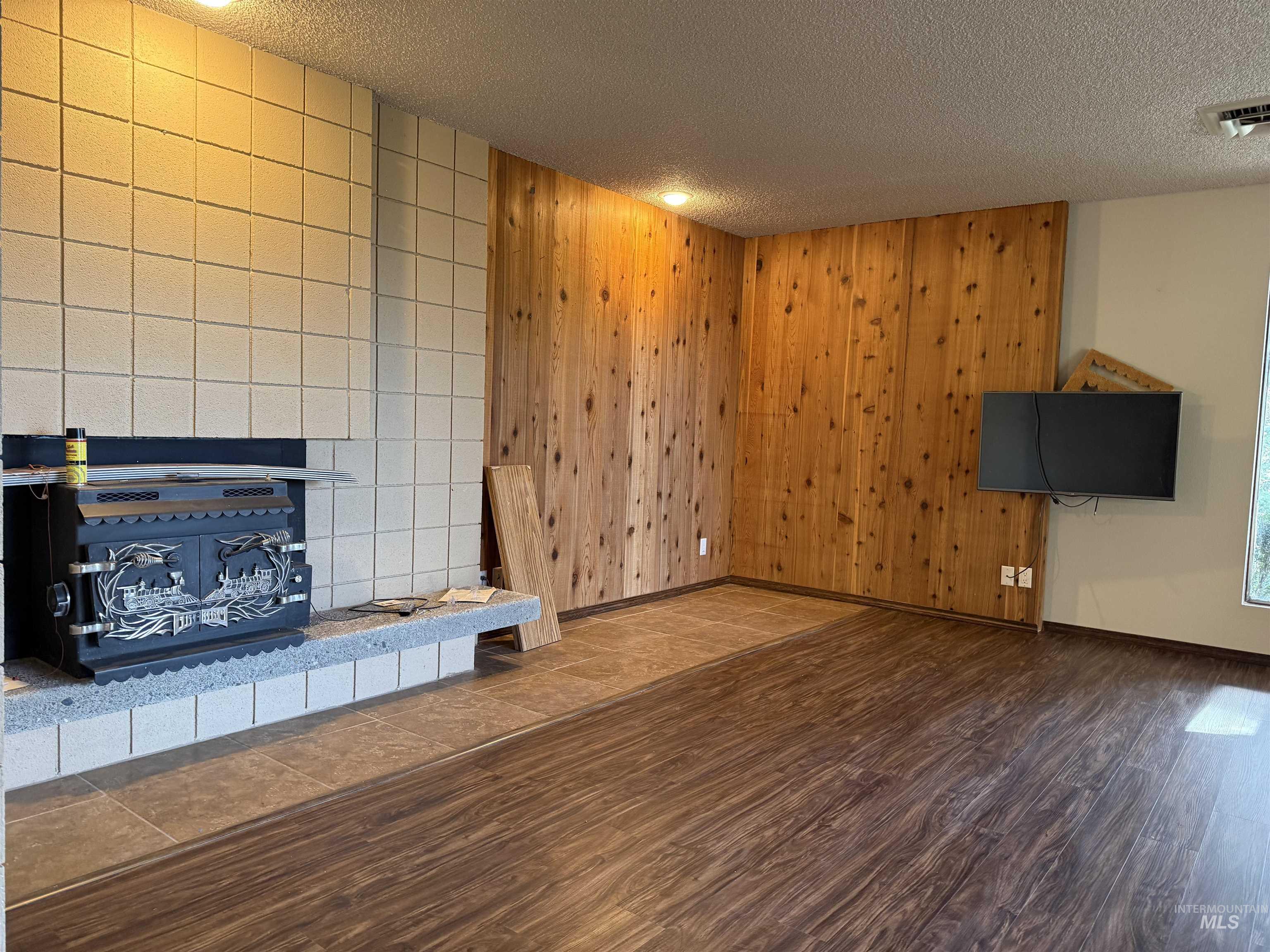 1050 Paradise Ridge Road Moscow, ID 83843 - Photo 27 of 49 Unfurnished living room featuring a textured ceiling, wooden walls, and wood finished floors