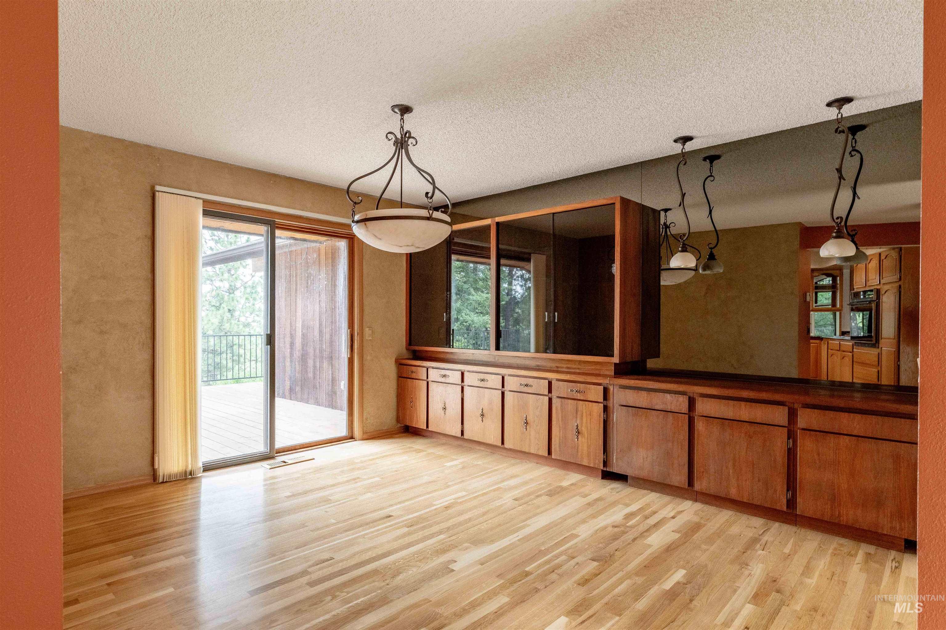 1050 Paradise Ridge Road Moscow, ID 83843 - Photo 9 of 49 Unfurnished dining area with light wood finished floors, a textured ceiling, and a textured wall