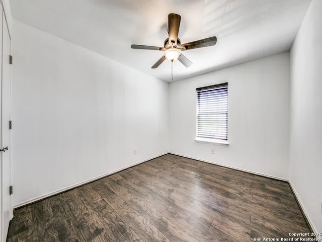 a view of empty room with wooden floor and ceiling fan