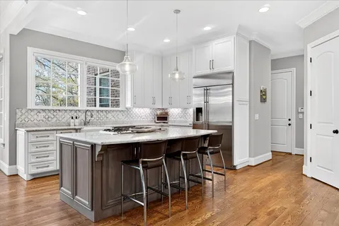 a kitchen with kitchen island wooden cabinets and refrigerator