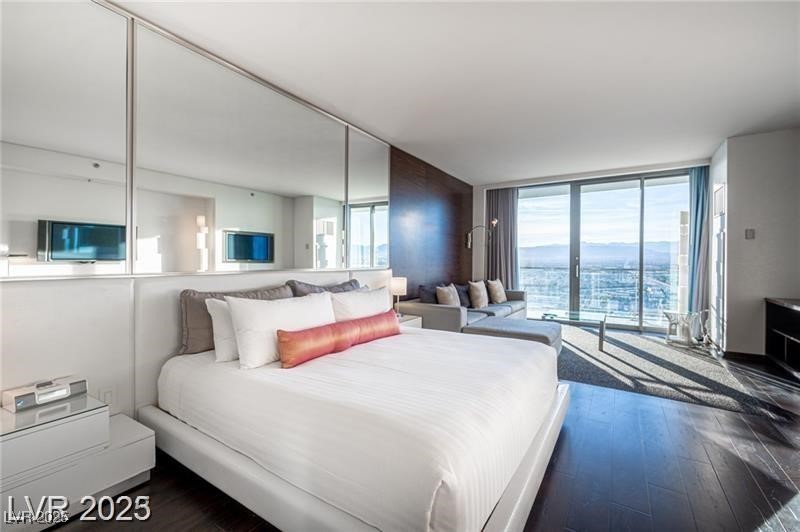 4381 West Flamingo Road, Unit 3303 Las Vegas, NV 89103 - Photo 1 of 37 Bedroom featuring a wall of windows and dark wood finished floors