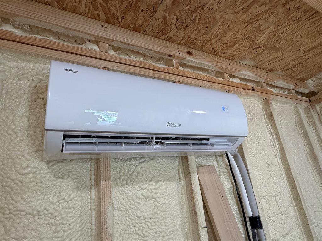 505 Thomas Street Terrell, TX 75160 - Photo 16 of 38 White wall-mounted HVAC unit with exposed wood framing and spray foam insulation
