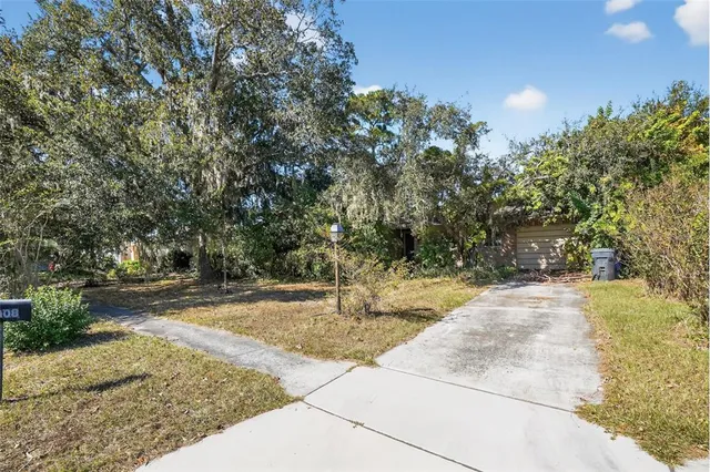 a backyard of a house with large trees and plants