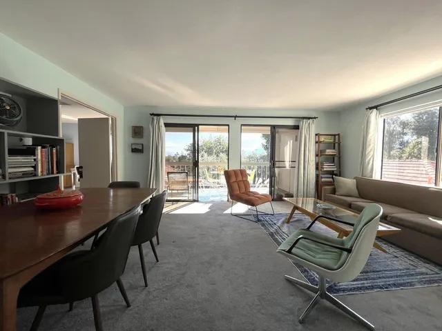 a living room with furniture a flat screen tv and a floor to ceiling window