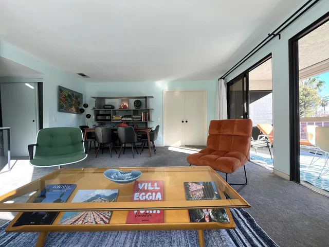 a living room with furniture a rug dining table and a large window