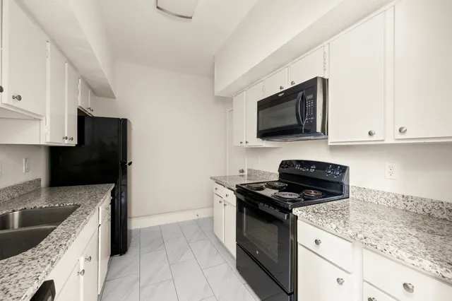 a kitchen with granite countertop stainless steel appliances a stove a sink and a microwave