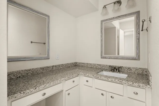 a bathroom with a granite countertop sink and a mirror