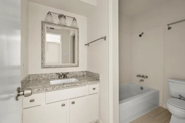 a bathroom with a granite countertop sink a toilet and a mirror