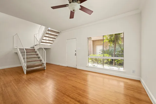 a view of an empty room with a window and wooden floor