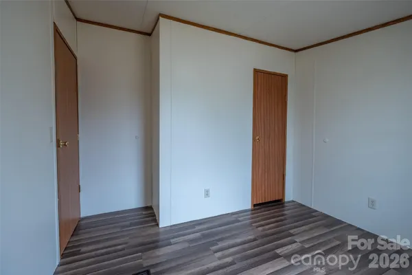 a view of an empty room with wooden floor and closet