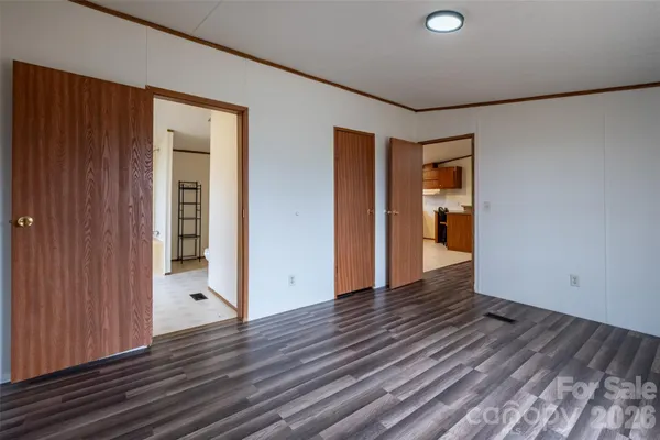 a view of an empty room with wooden floor and closet