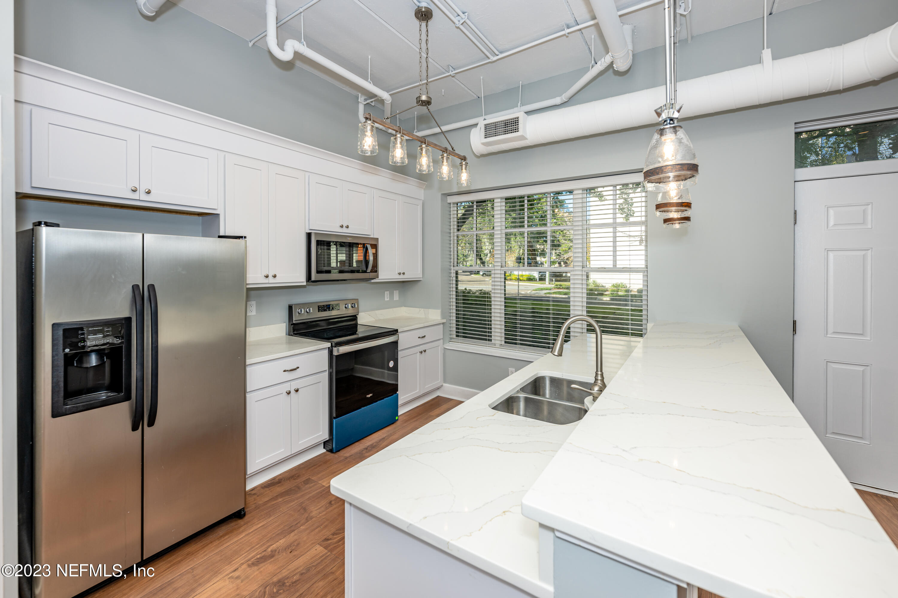1661 Riverside Avenue, Unit 119 Jacksonville, FL 32204 - Photo 12 of 45 a kitchen with granite countertop a refrigerator a sink a stove and white cabinets with wooden floor
