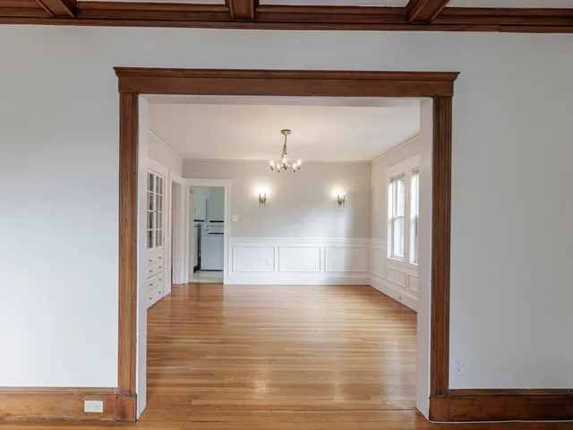 a view of an empty room with window and wooden floor