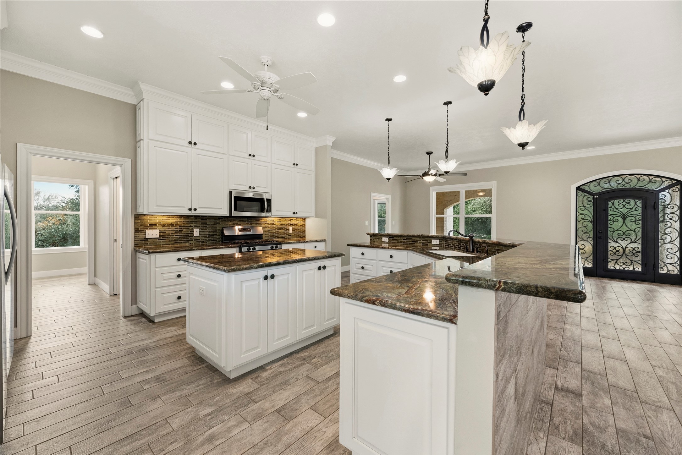 2051 Hillview Road Bellville, TX 77418 - Photo 16 of 47 Gourmet island kitchen features white cabinetry, glass tile backsplash, marble countertops, under cabinet lighting, stainless steel appliances, gas range, lovely pendant lighting and a large breakfast bar with seating up to 8.