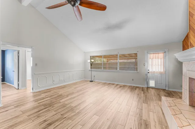 a view of an empty room with wooden floor and a window