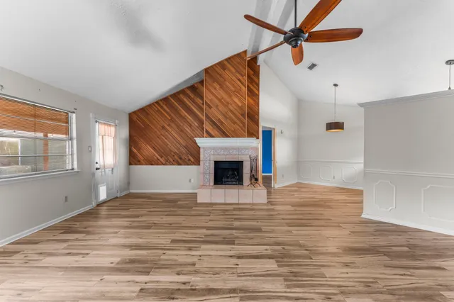 a view of empty room with wooden floor and fan