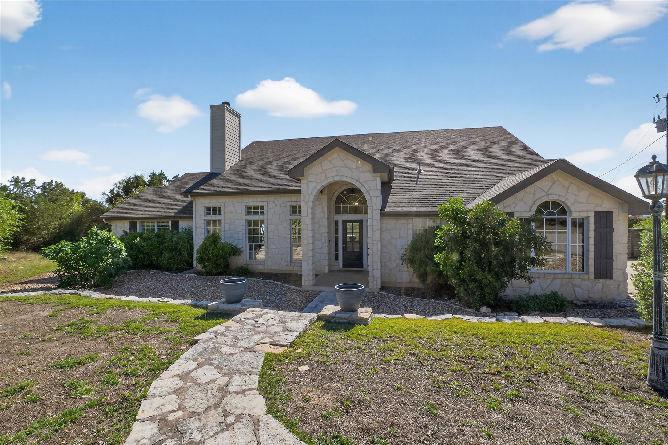 13624 Trautwein Road Austin, TX 78737 - Photo 5 of 38 An inviting stone pathway guides you to the welcoming arched entryway of this charming residence.