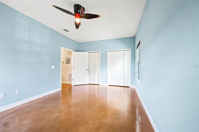 an empty room with ceiling fan and window