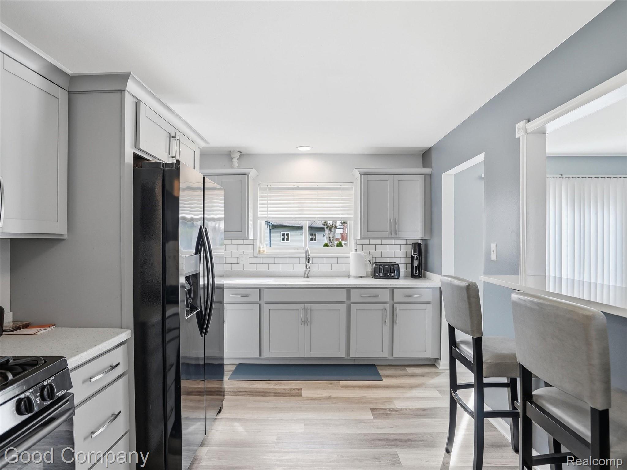 30632 Hayes Road Roseville, MI 48066 - Photo 14 of 32 Contemporary kitchen featuring light gray cabinetry, stainless steel appliances, white subway tile backsplash, light wood-finish flooring, and white countertops