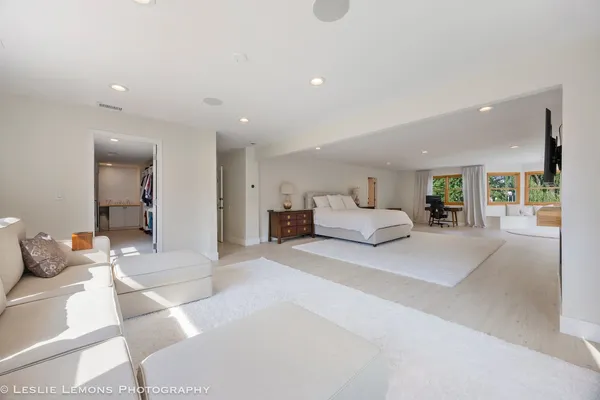 a spacious bedroom with a bed and a flat screen tv