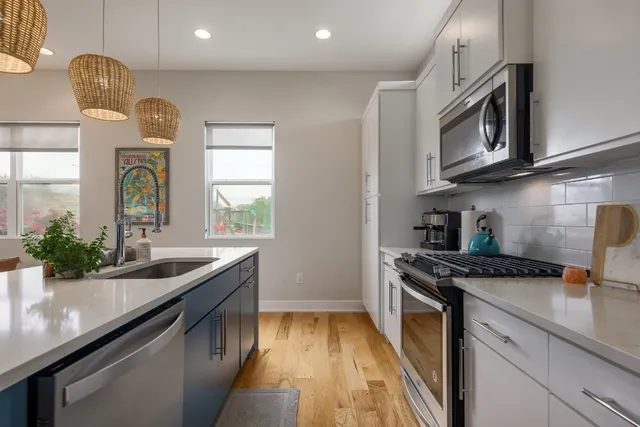 a kitchen with stainless steel appliances granite countertop a sink a stove and a wooden cabinets
