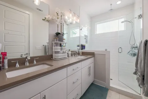 a bathroom with a double vanity sink mirror and shower