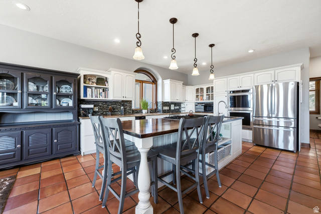 335 Bern Way Midway, UT 84049 - Photo 20 of 88 Spacious kitchen featuring terracotta tile flooring, white cabinetry, stainless steel appliances, a center island with wood-finish countertop, and pendant lighting