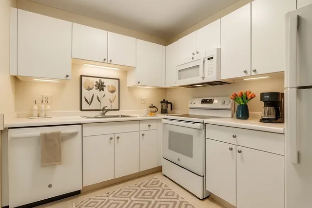 a kitchen with white cabinets and white appliances