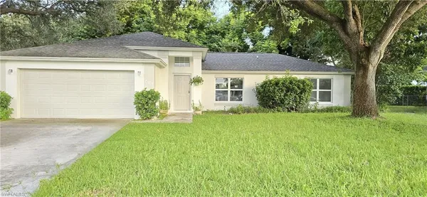 a view of a house with a yard and large tree
