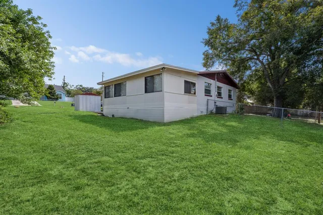a house that is sitting in the grass and the view of trees in the background