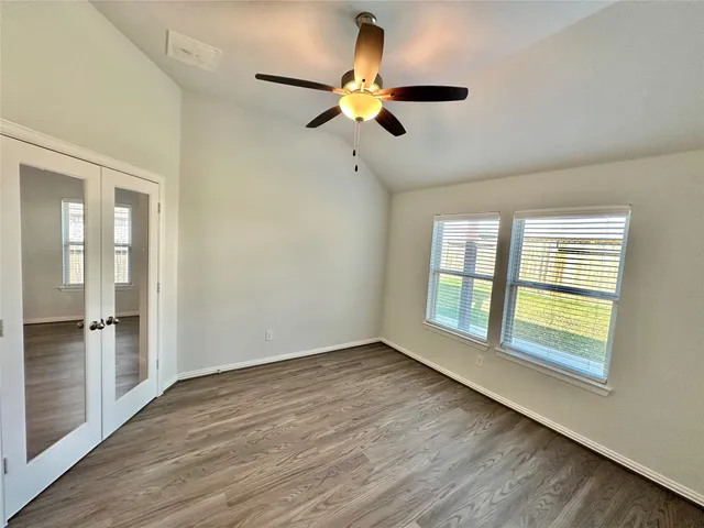 a view of an empty room with a window and wooden floor