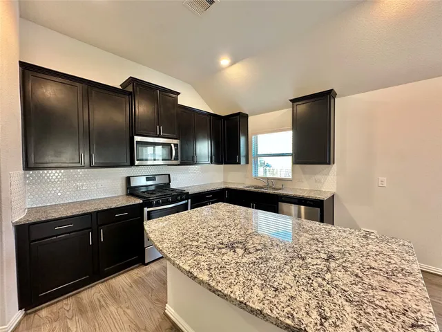 a kitchen with stainless steel appliances kitchen island granite countertop a stove and a sink